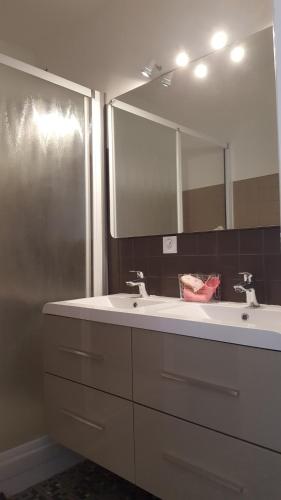 une salle de bain avec deux lavabos et un grand miroir dans l'établissement Paraire, à Rodez