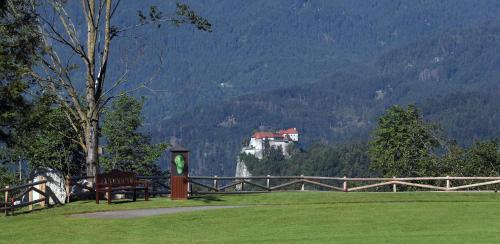 a park with a bench and a castle in the mountains at King's and Lake's House Golf Course Royal Bled in Bled