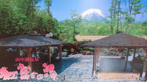a snow covered mountain in the distance behind two gazebos at Inn Yamanami in Yamanakako