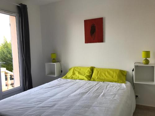 une chambre avec un lit avec des oreillers jaunes et une fenêtre dans l'établissement Bastide dans le Var, à Flayosc