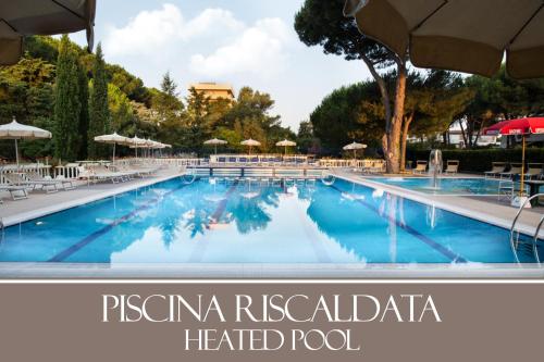 a large swimming pool with chairs and umbrellas at Park Hotel Marinetta - Beach & Spa in Marina di Bibbona