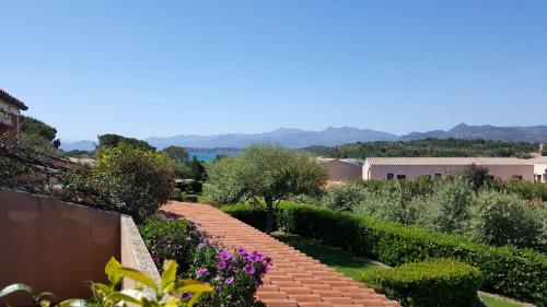 a garden with a brick walkway with purple flowers at Residenze Coda Cavallo in San Teodoro