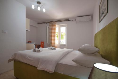 1 dormitorio con 1 cama blanca grande y toallas. en Apartments Grand, en Sveti Stefan
