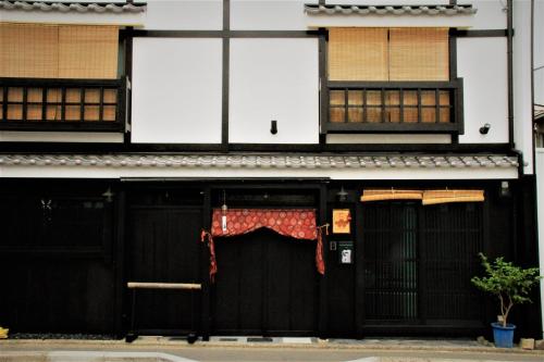 a building with black doors with a red curtain on it at 京町家-椿庵Kyomachiya-Tsubakian in Kyoto