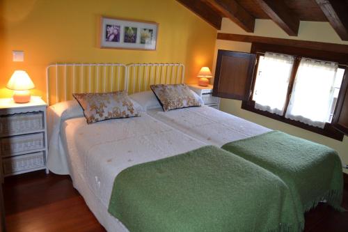 a bedroom with a large white bed with two windows at Apartamentos La Buhardilla in Ezcaray