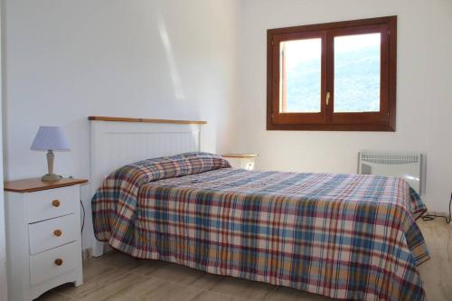 una camera da letto con un letto con una coperta scozzese e una finestra di Apartament a Capafonts - "Ribatell" a Capafons