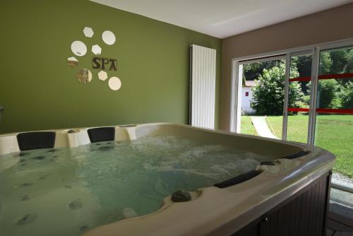 a jacuzzi tub in a room next to a window at Logis Hôtel Andreinia & Cabanes in Esterençuby