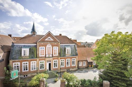 a large brick building with white windows and a church at Burghotel Haselünne in Haselünne