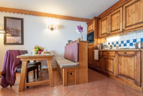 une cuisine avec des armoires en bois et une petite table dans l'établissement Résidence Pierre & Vacances Premium Les Hauts Bois, à Aime La Plagne