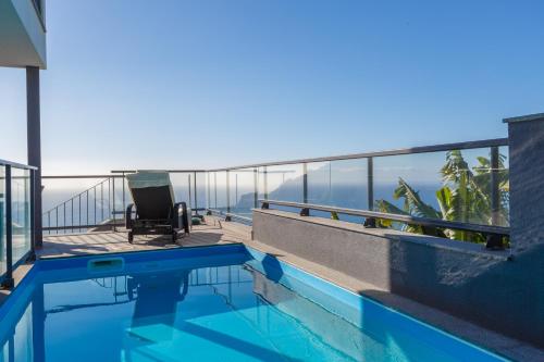 a balcony with a pool and a chair on a building at Villa Maciel in Calheta