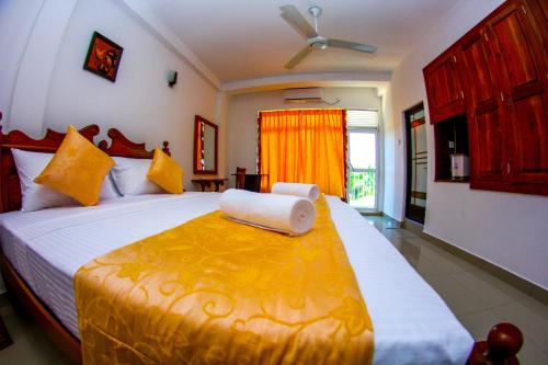 a bedroom with a large bed with a yellow blanket at Niwahana Transit City Hotel in Katunayaka