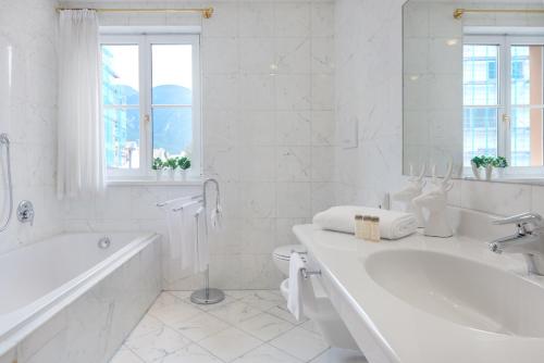 a white bathroom with a bath tub and a toilet at Hotel Goldene Rose in Brunico