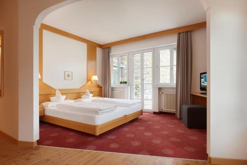 a bedroom with a large bed and a large window at Hotel Goldene Rose in Brunico