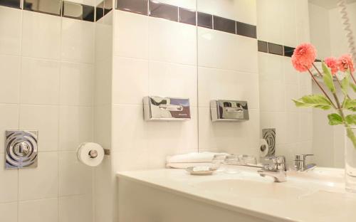La salle de bains est pourvue d'un lavabo et d'un vase fleuri. dans l'établissement A-Hotel Oosterhout, à Oosterhout