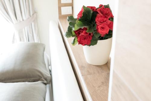 a white vase filled with red roses in a room at Relais Dei Mandorli in Bergamo