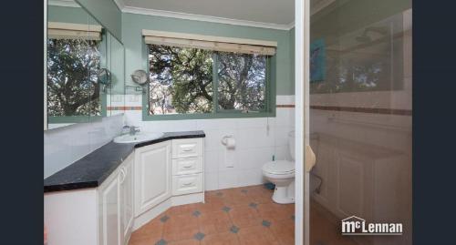 a bathroom with a toilet and a sink and a mirror at 6 Bedrooms/9 Beds Huge House|City+Park Views|Beach in Frankston