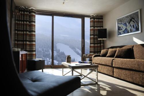a living room with a couch and a large window at CGH Résidence Boutique Le Centaure in Flaine