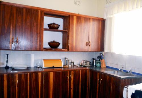 una cocina con armarios de madera y fregadero en Tinotenda Cottage en Harare