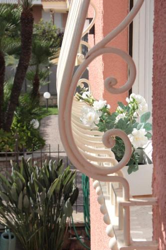 a white bench on a balcony with flowers on it at B&B Villa Mirella in Bordighera