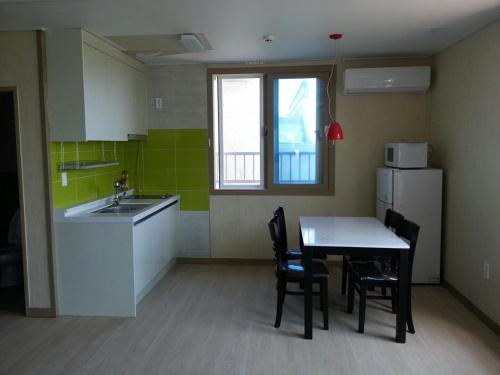 a kitchen with a table and a sink and a refrigerator at Seongsan Morning Sunset in Seogwipo