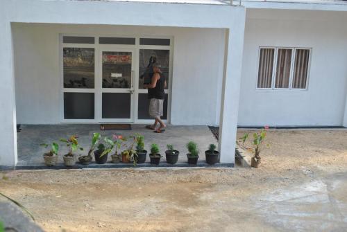 a man standing in front of a door with potted plants at Mountain Villa Adam's Peak in Adams Peak