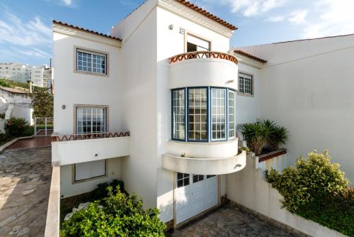 a white house with balconies and plants at Casa das Conchas in Ericeira