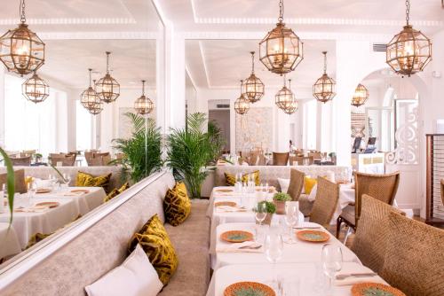 un restaurant avec des tables et des chaises blanches et des lustres dans l'établissement La Palmeraie, à La Baule