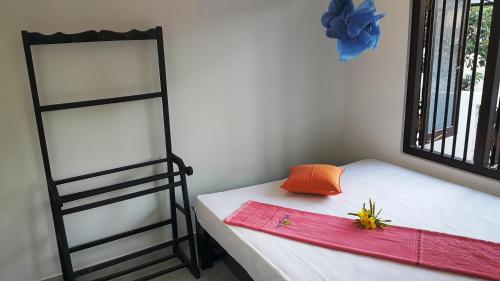 a room with a bed and a shelf with a hat on it at Green Garden Guest Mirissa in Mirissa