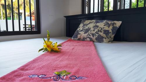 a pink blanket with a flower on a bed with a pillow at Green Garden Guest Mirissa in Mirissa