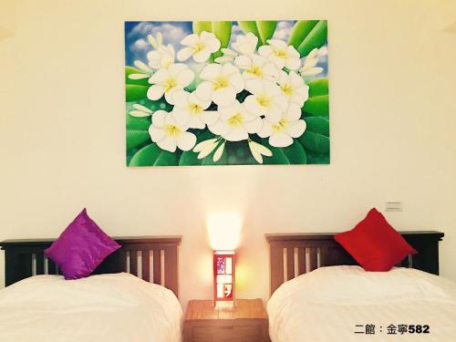 two beds in a room with a painting on the wall at Home & Teak Homestay in Jinning