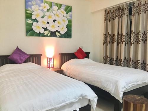 two beds in a room with a painting on the wall at Home & Teak Homestay in Jinning