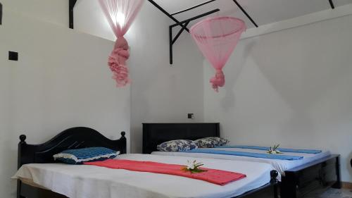 two beds in a room with pink and blue sheets at Green Garden Guest Mirissa in Mirissa