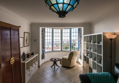 a living room with a large window and a chair at Casa das Conchas in Ericeira