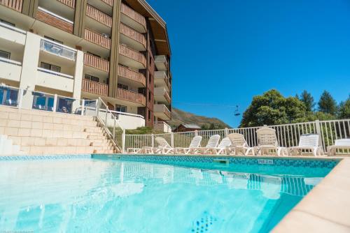 - une piscine en face d'un bâtiment avec des chaises dans l'établissement Résidence Pierre & Vacances Les Bergers, à L'Alpe-d'Huez