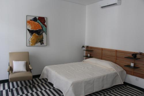 a bedroom with a bed and a chair at DoBairro suites at Bairro Alto in Lisbon