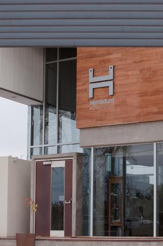 a building with a sign for a hotel at Herradura Hotel Suites in Neuquén