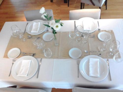 a white table with plates and glasses and flowers on it at Herradura Hotel Suites in Neuquén