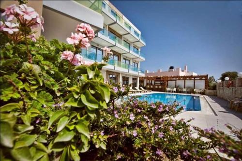 un bâtiment avec une piscine et quelques fleurs roses dans l'établissement Crystal Bay Hotel, à Kíssamos