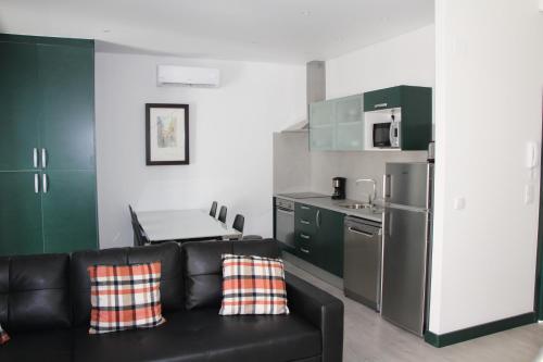 a living room with a black couch and a kitchen at DoBairro suites at Bairro Alto in Lisbon