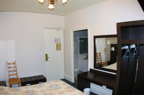 a bedroom with a bed and a mirror and a desk at Hotel de la Basilique in Paray-le-Monial