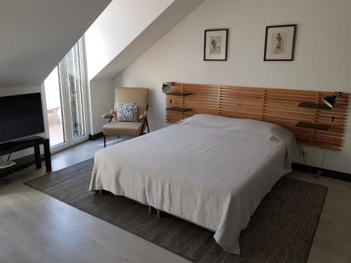 a bedroom with a bed and a chair and a television at DoBairro suites at Bairro Alto in Lisbon