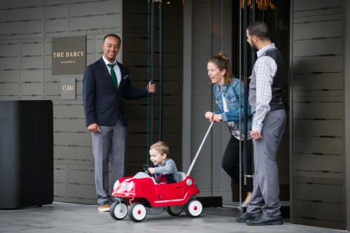 a group of people standing around a baby in a red wagon at The Darcy Hotel, Washington DC in Washington