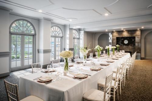 - une longue table dans une pièce avec des tables et des chaises blanches dans l'établissement The Darcy Hotel, Washington DC, à Washington