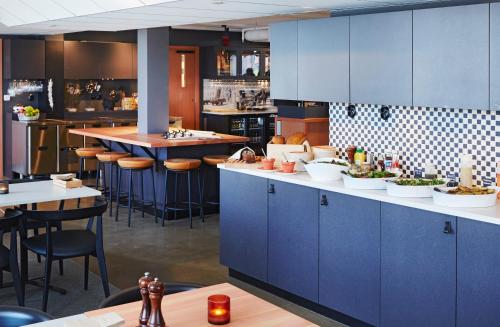 a large kitchen with blue cabinets and bar stools at Home Hotel Magasinet in Trelleborg