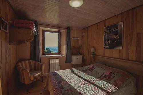 een slaapkamer met een bed, een stoel en een raam bij Gîte " Orée des bois" in Vertolaye