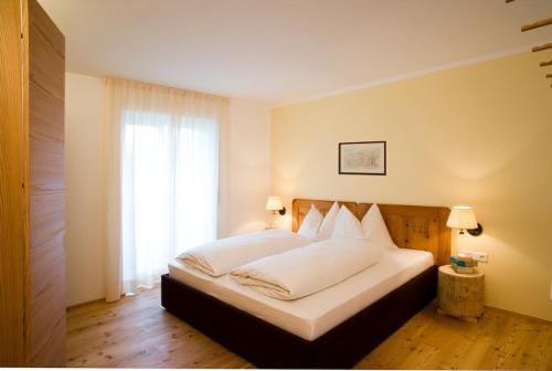 a bedroom with a bed with white sheets and a window at Residence Gustav Thoeni in Prato allo Stelvio
