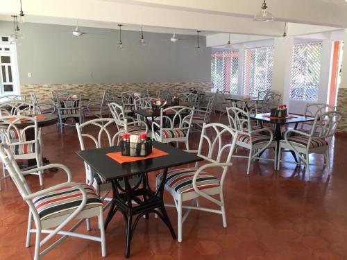 a dining room with tables and white chairs at Hotel Alicia Beach in Sosúa