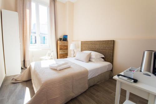 een slaapkamer met een bed met witte lakens en een televisie bij Emily Rooms in Sanremo