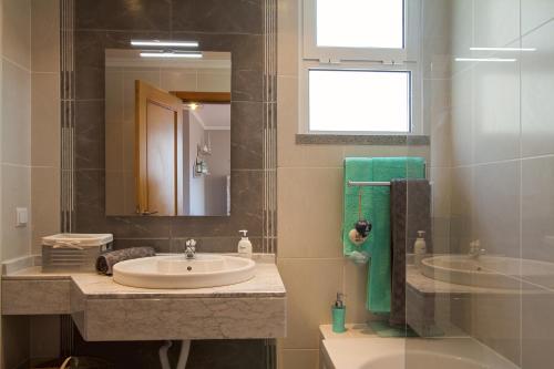 a bathroom with a sink and a tub and a mirror at Peace Haven in Calheta