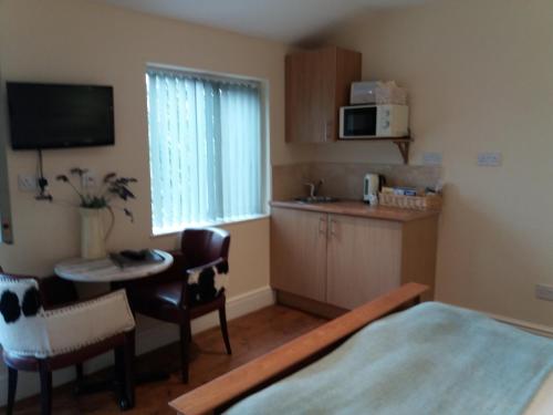 a room with a bed and a table and a kitchen at The Stables - Deer Park Farm in Solihull